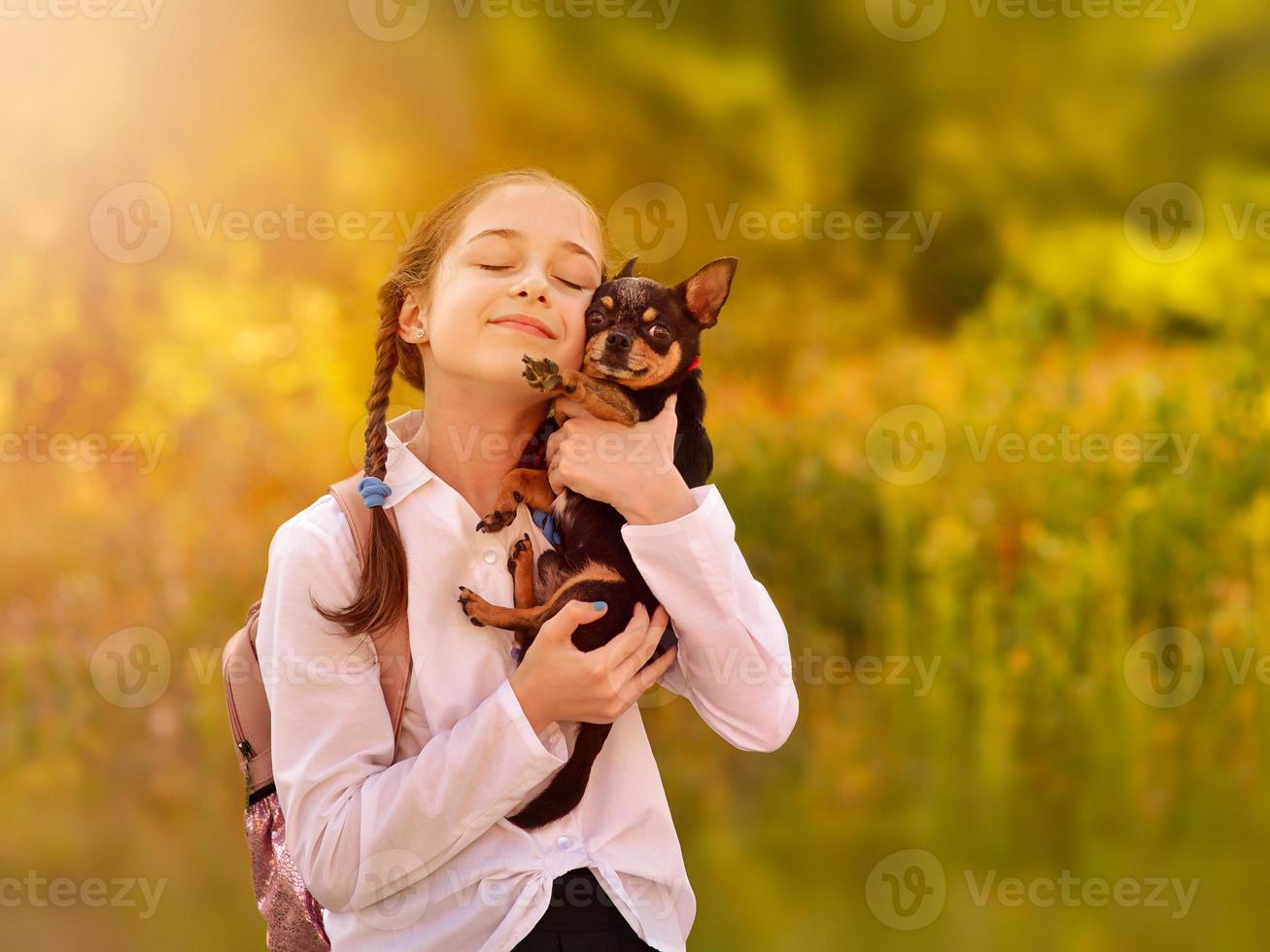 menina criança colegial segurando e brincando com o cachorro de estimação. amigos. foto