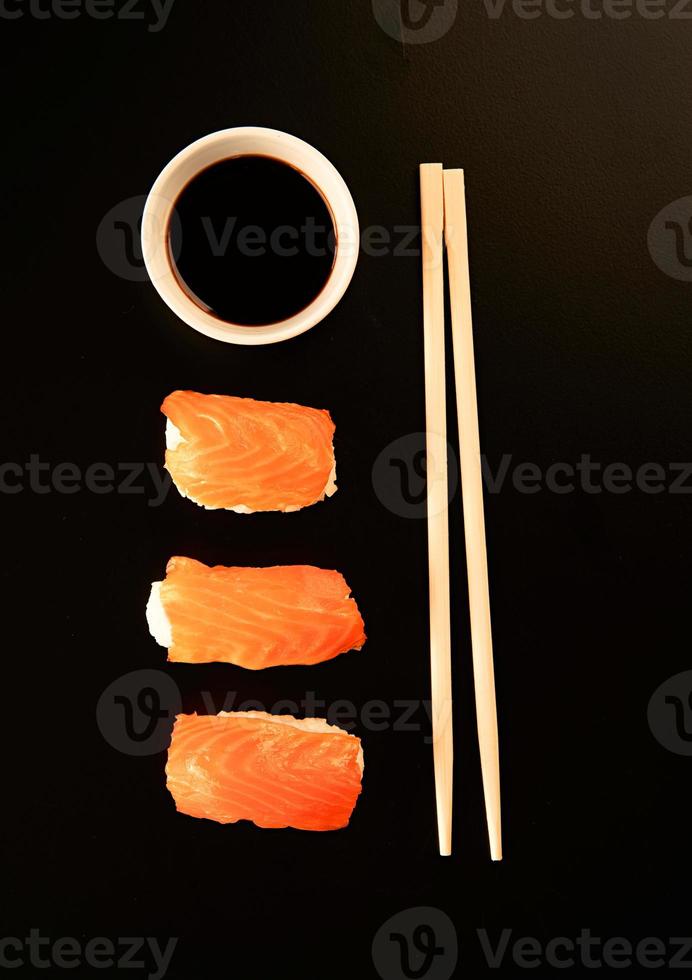 conjunto de rolos de sushi e pauzinhos, isolado no fundo preto foto