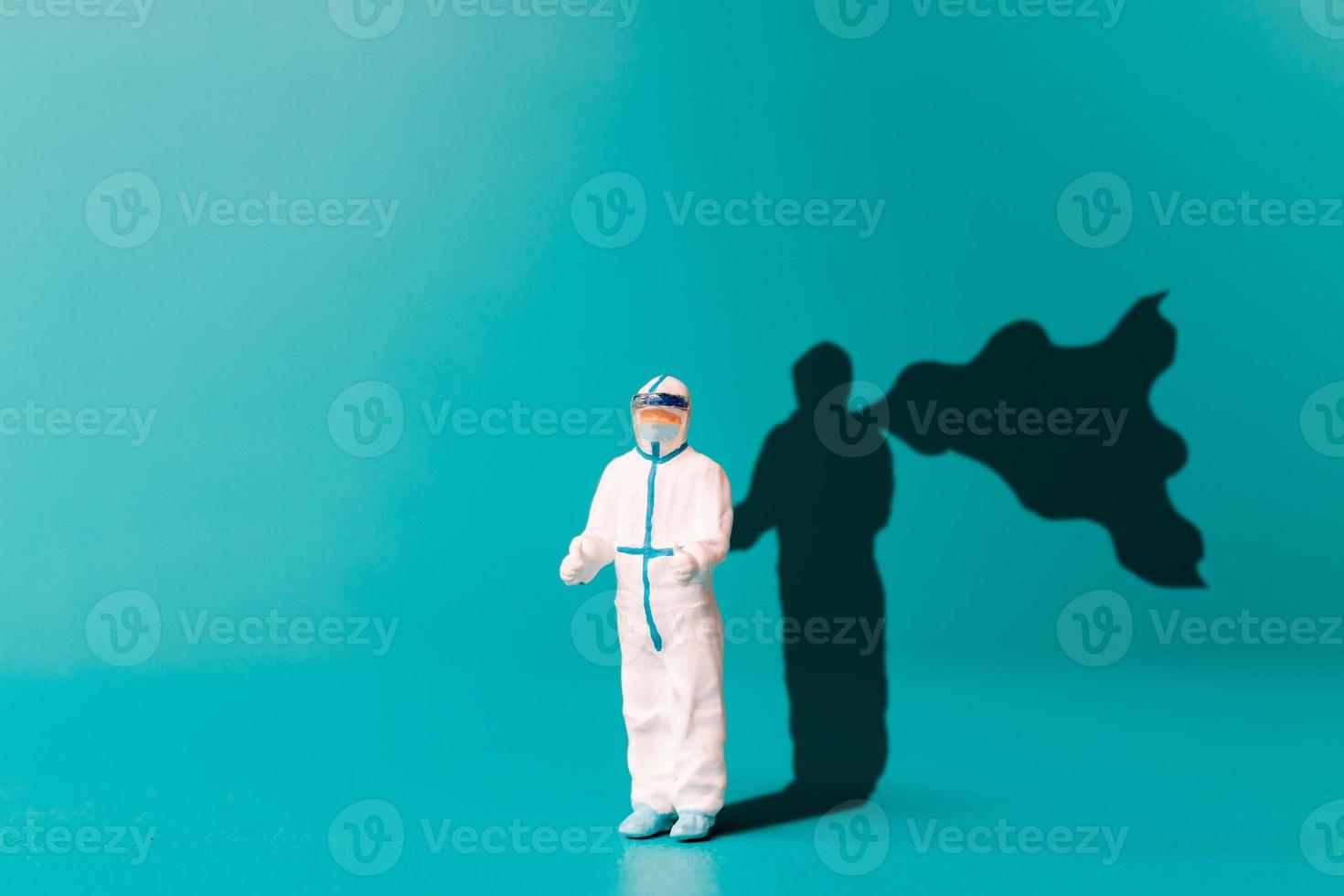 médico de pessoas em miniatura com sombra de super-herói na parede. foto
