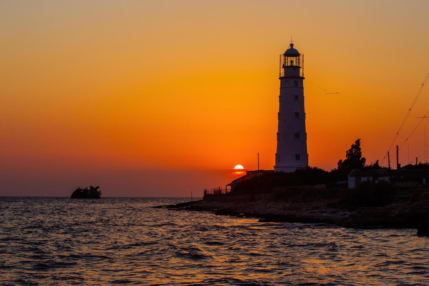 farol na costa do mar ao pôr do sol foto