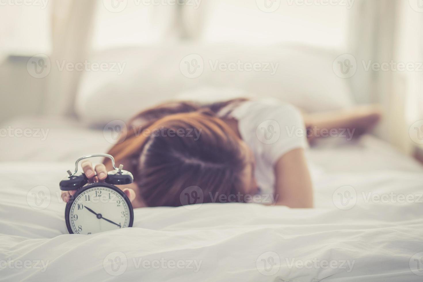 jovem mulher asiática desligar o despertador em bom dia. foto