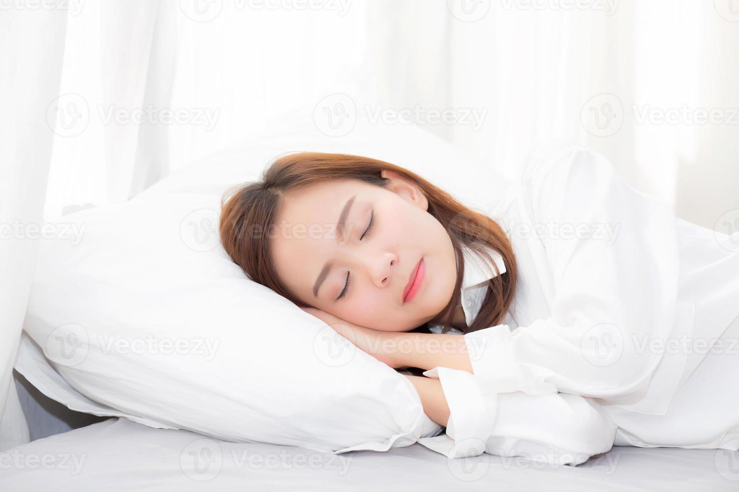 jovem mulher asiática dormindo deitada na cama no quarto. foto