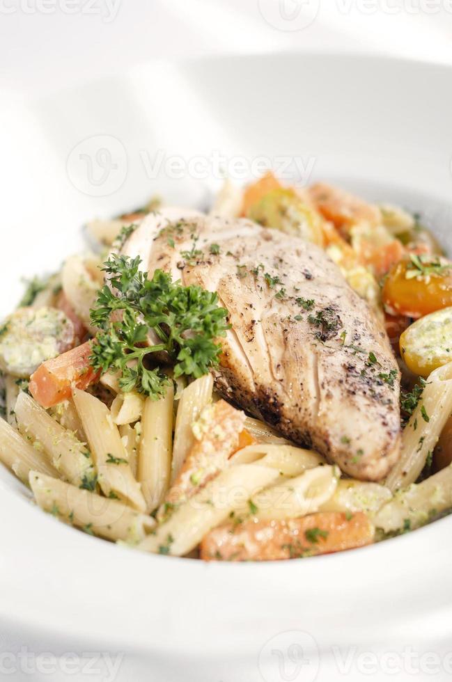 peito de frango frito com penne e prato de massa de legumes refogados no fundo branco foto