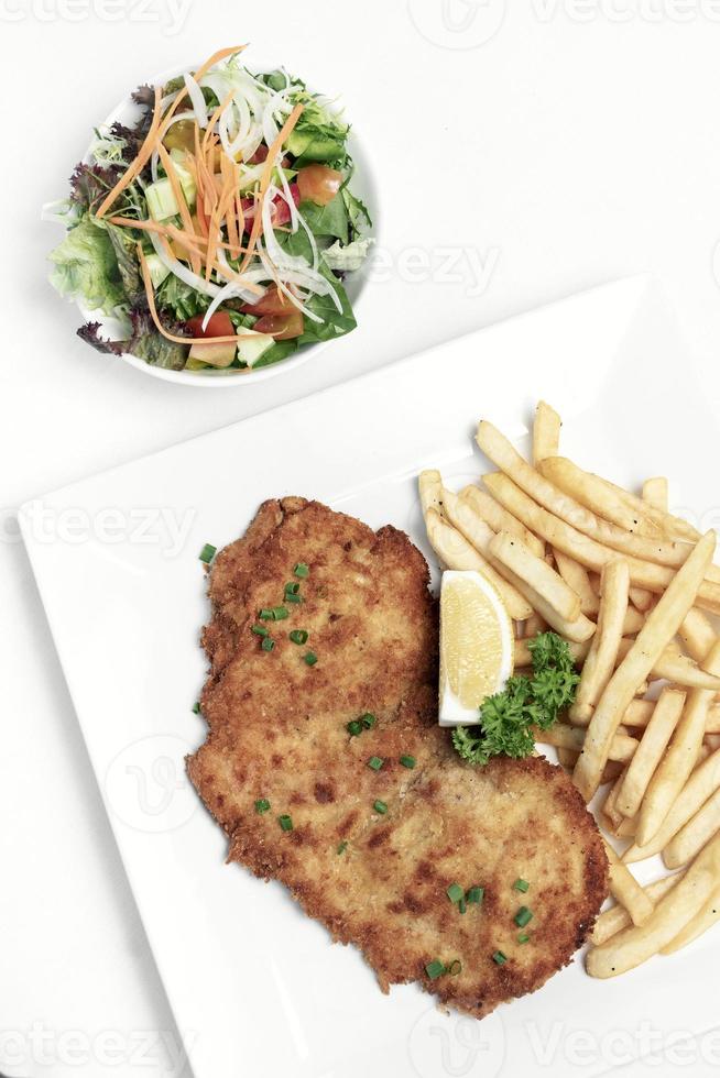 Schnitzel de porco à milanesa com batatas fritas no fundo branco do estúdio foto