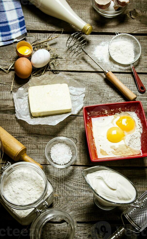 preparação do a massa. ingredientes para a massa - leite, creme, manteiga, farinha, sal, ovos e diferente ferramentas. foto