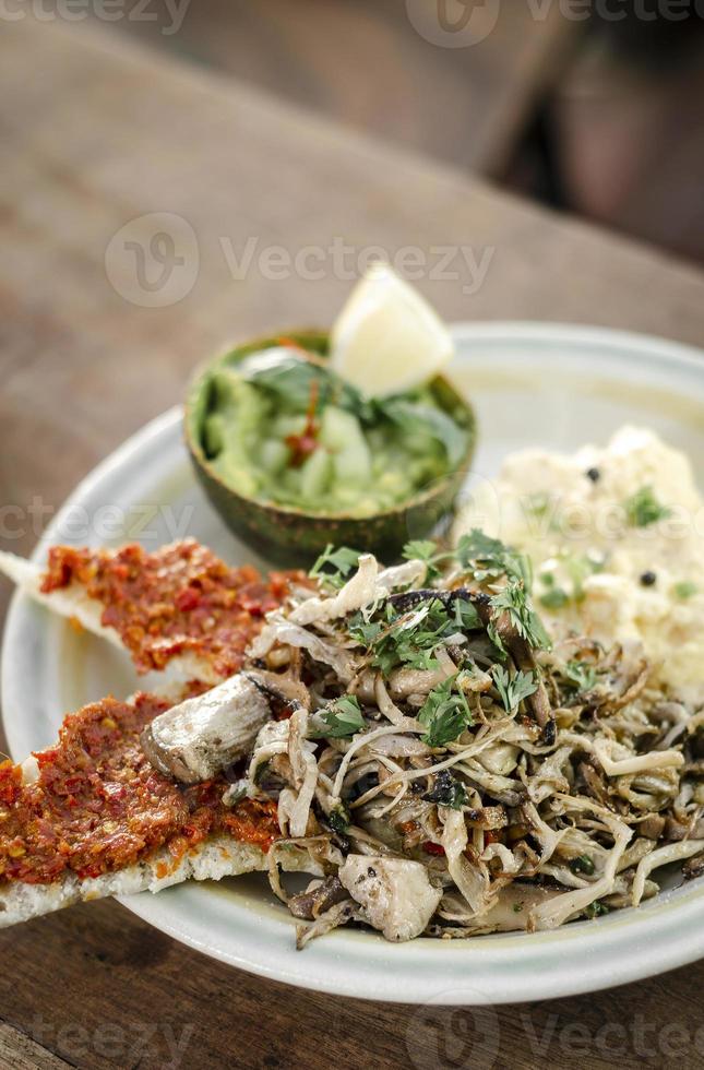 brunch mexicano moderno de cogumelos fritos com guacamole e torrada com pasta de pimenta vermelha picante e ovos mexidos foto