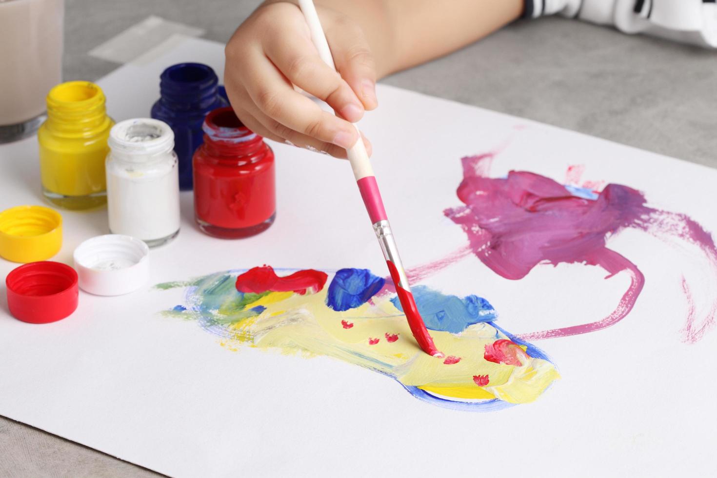 menino asiático usando pincel e aquarela em papel foto