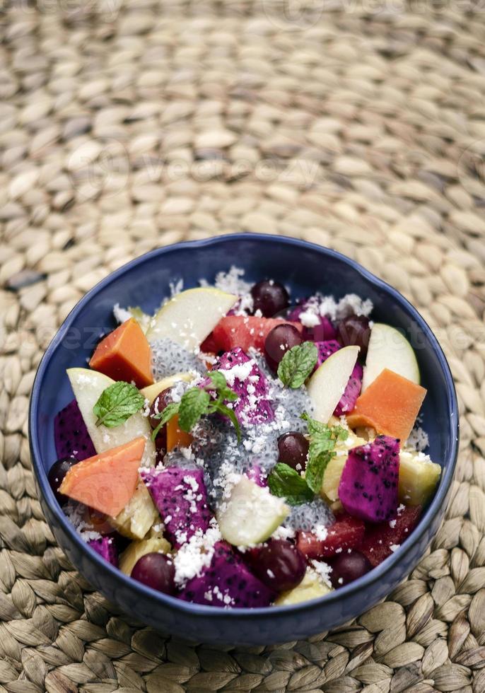 Salada de frutas tropicais asiáticas exóticas com sementes de manjericão e coco em uma tigela ao ar livre foto