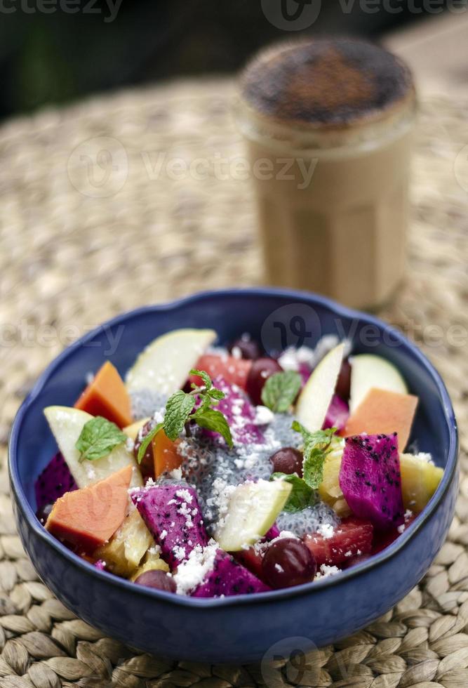 Salada de frutas tropicais asiáticas exóticas com sementes de manjericão e coco em uma tigela ao ar livre foto