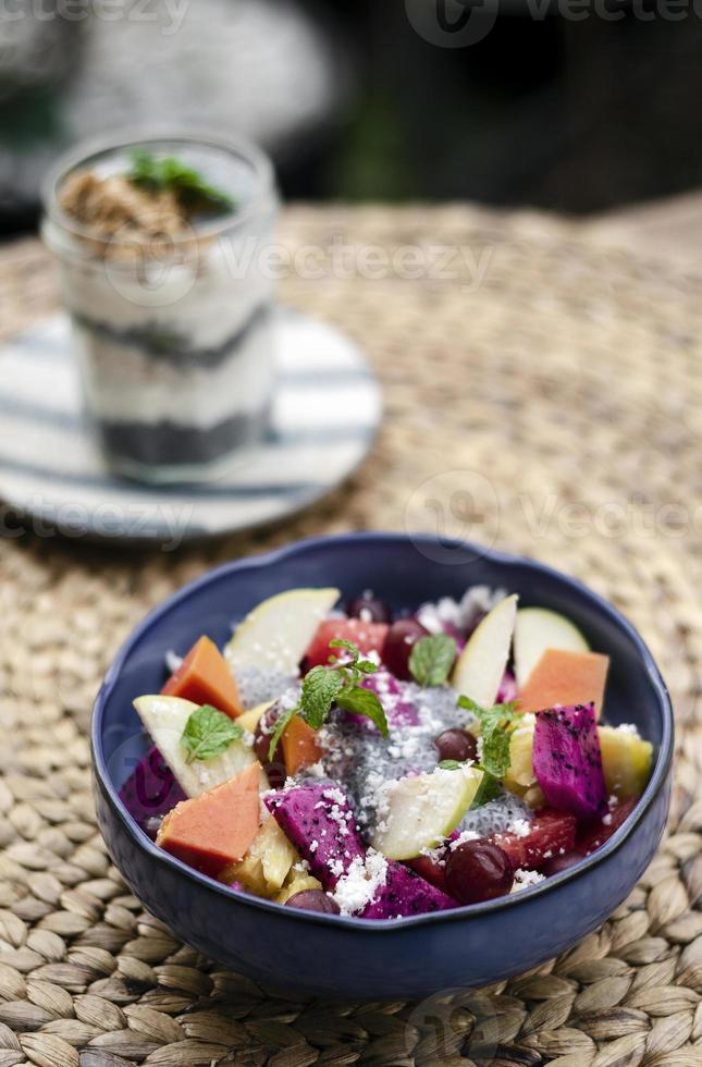 Salada de frutas tropicais asiáticas exóticas com sementes de manjericão e coco em uma tigela ao ar livre foto