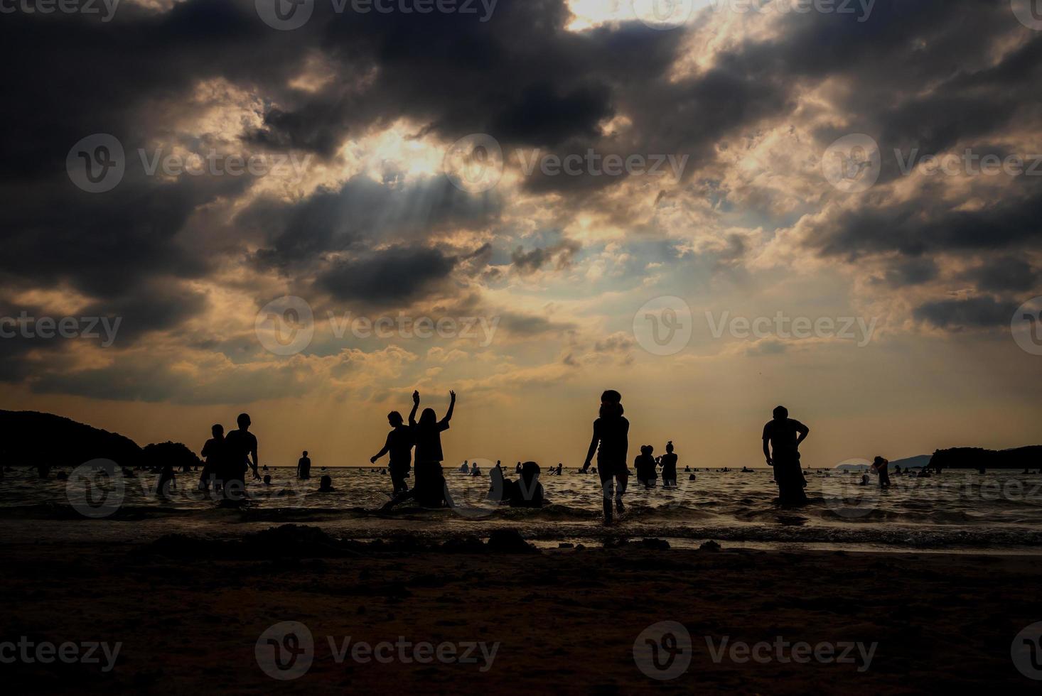 silhuetas de pessoas brincando no mar em uma praia pública foto