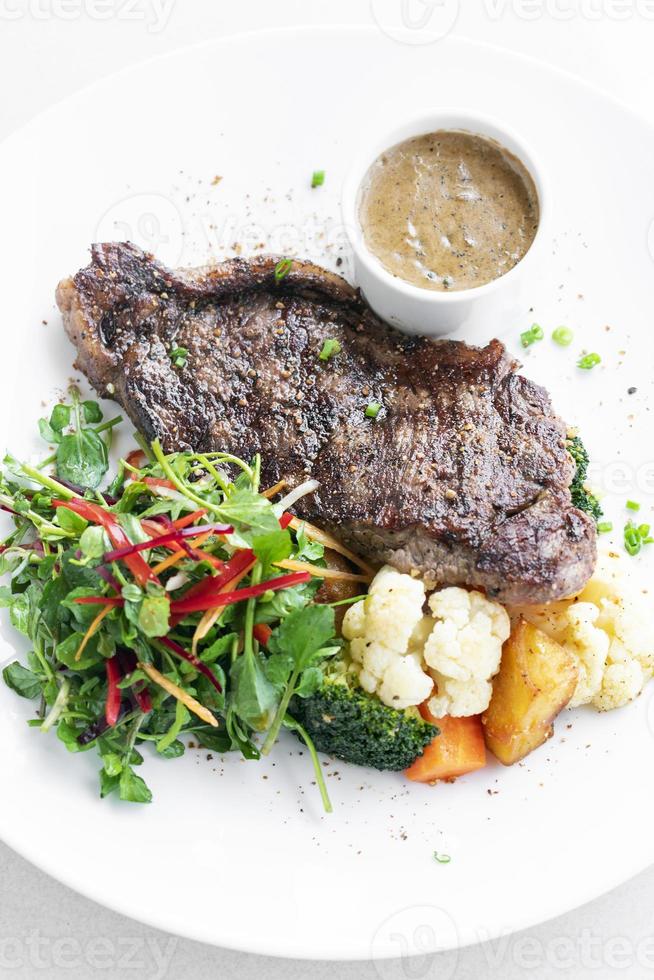 Bife premium com legumes cozidos no vapor e molho de cogumelos refeição gourmet em prato branco foto