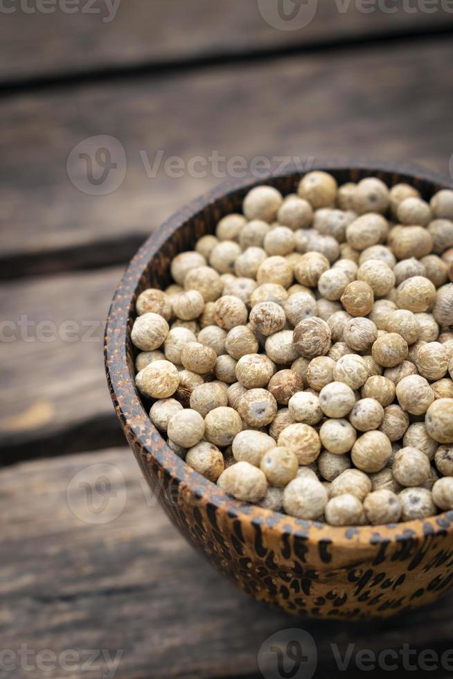 Kampot orgânico secou grãos de pimenta branca no Camboja em uma tigela de madeira tradicional asiática foto