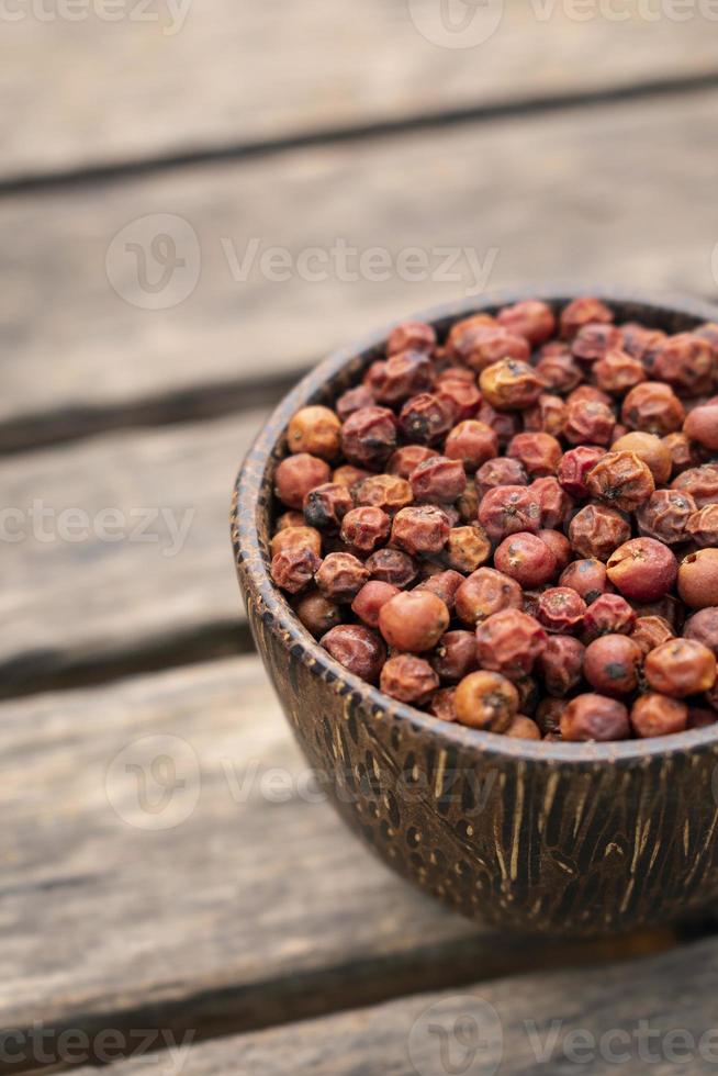 Kampot orgânico secou grãos de pimenta vermelha no Camboja em uma tigela de madeira asiática tradicional foto