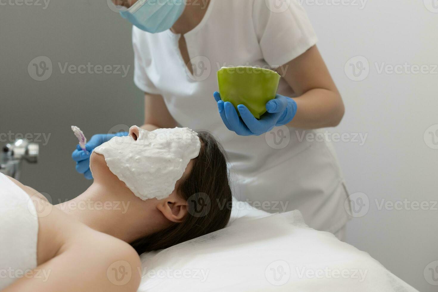 esteticista aplicando alginato mascarar em fêmea face foto