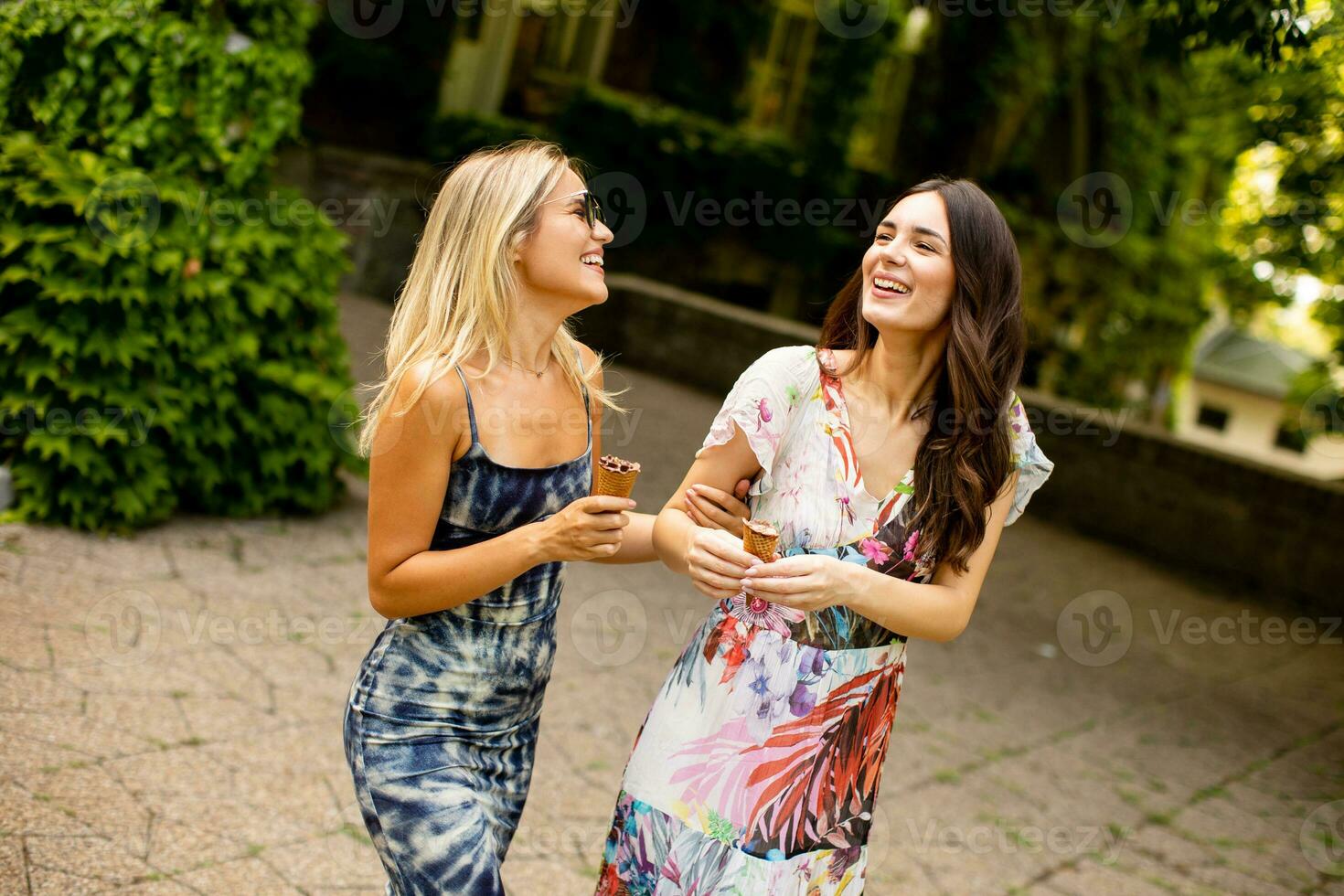 bonita jovem mulheres caminhando e comendo gelo creme de a velho casa com hera foto