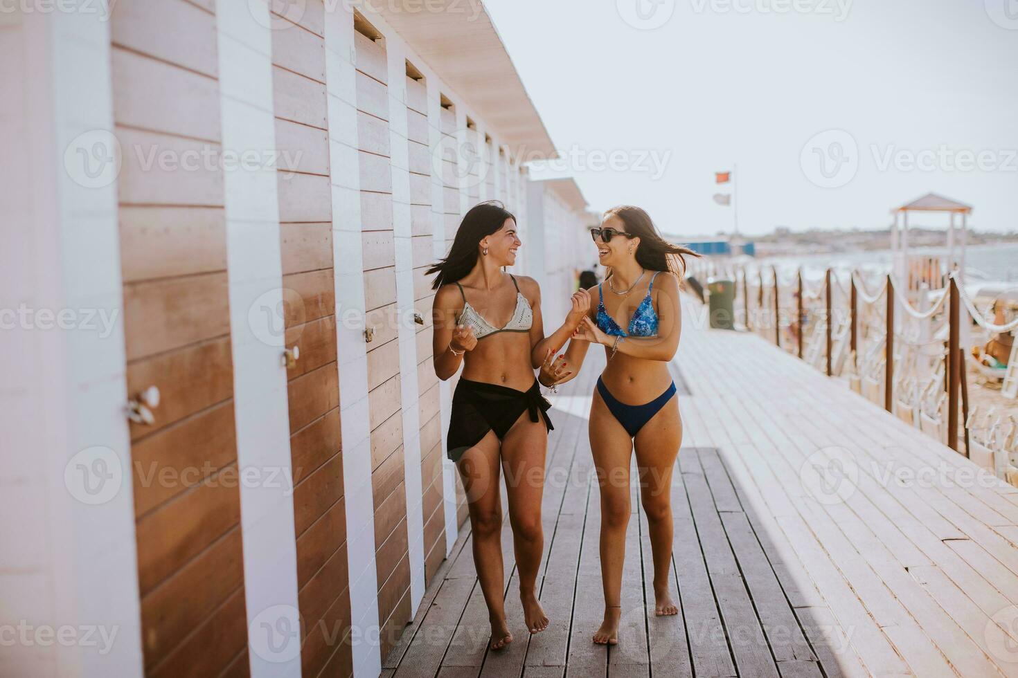 sorridente jovem mulheres dentro bikini desfrutando período de férias em a de praia foto