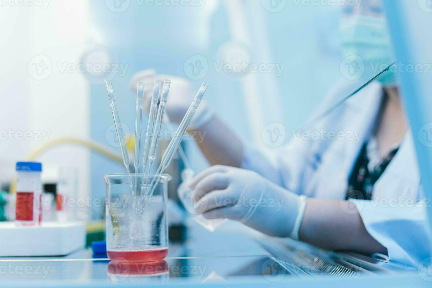 conta-gotas pipeta dentro taça e cientista usando conta-gotas pipeta transferir amostra dentro biossegurança gabinete em fundo. selecionar foco em taça foto