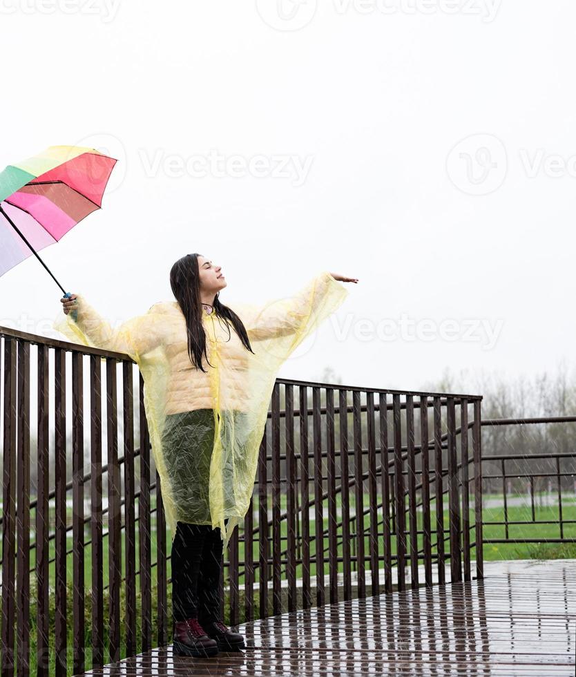 linda mulher morena segurando guarda-chuva colorido na chuva foto