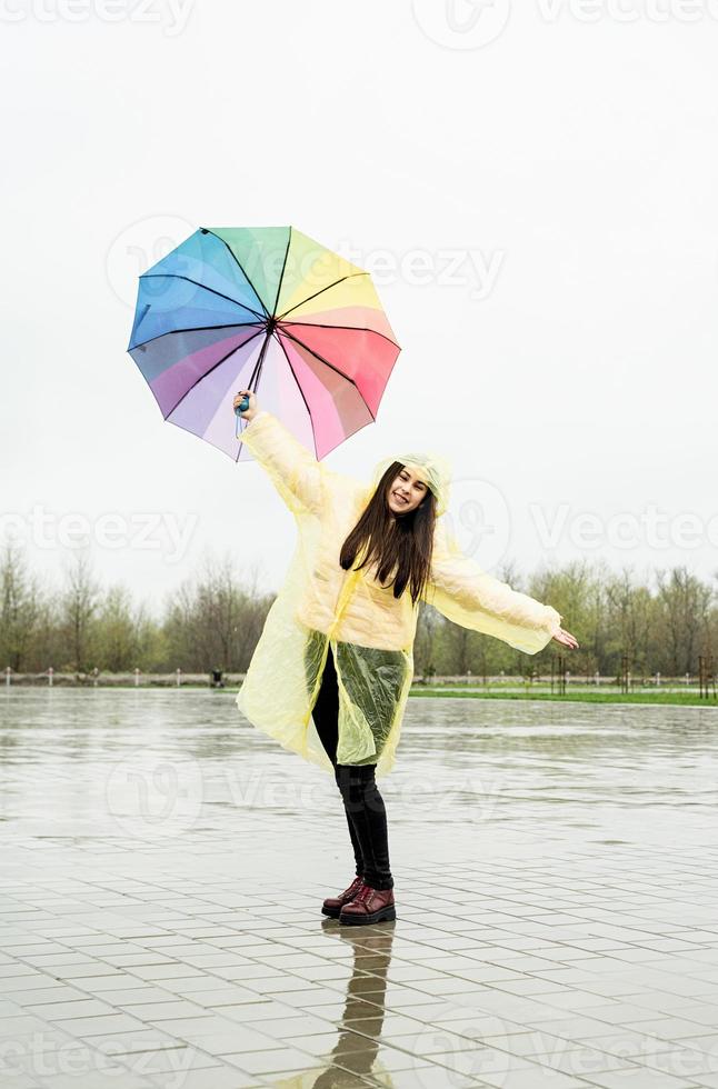 linda mulher morena segurando guarda-chuva colorido na chuva foto
