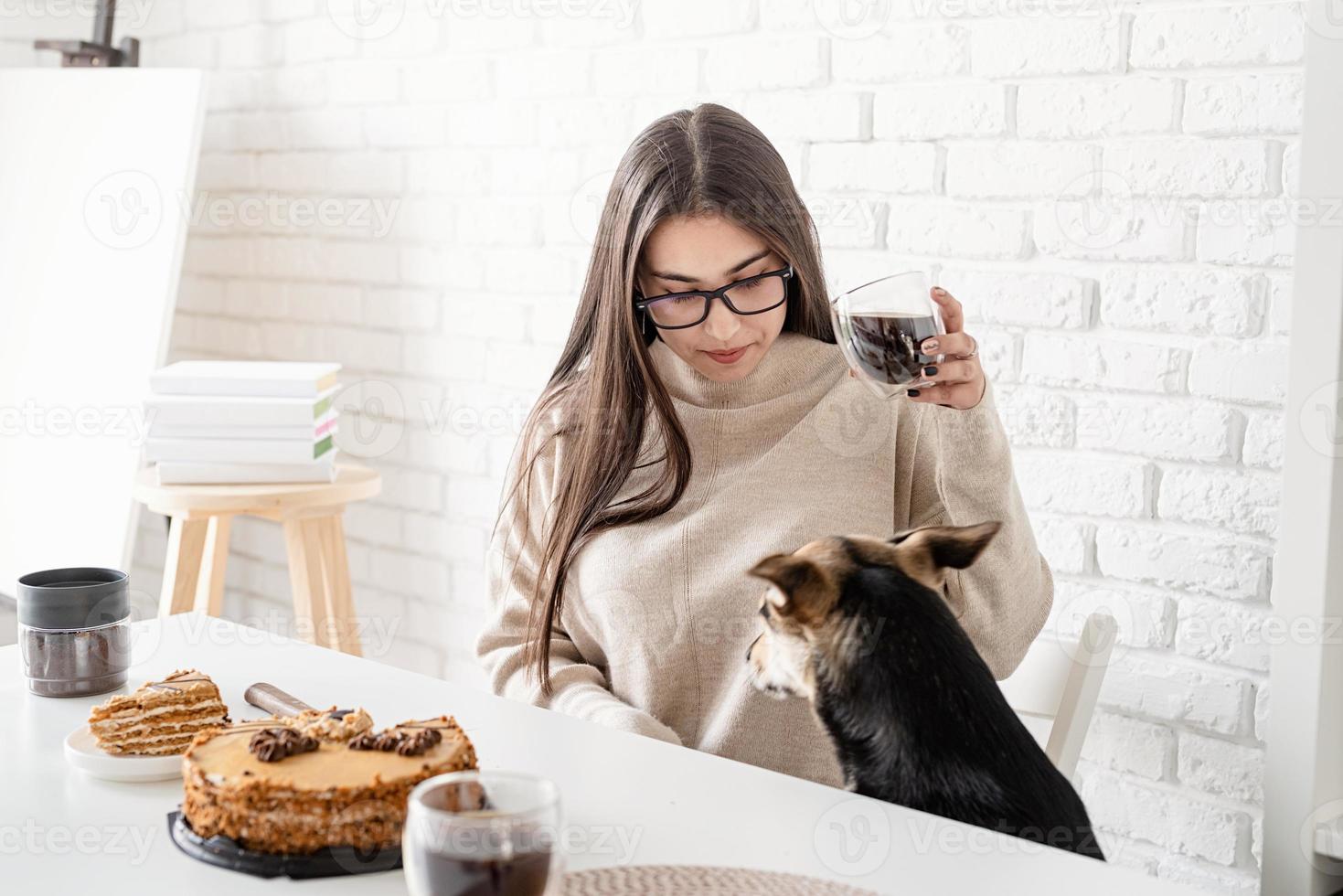 jovem bebendo café preto quente sentada à mesa branca foto