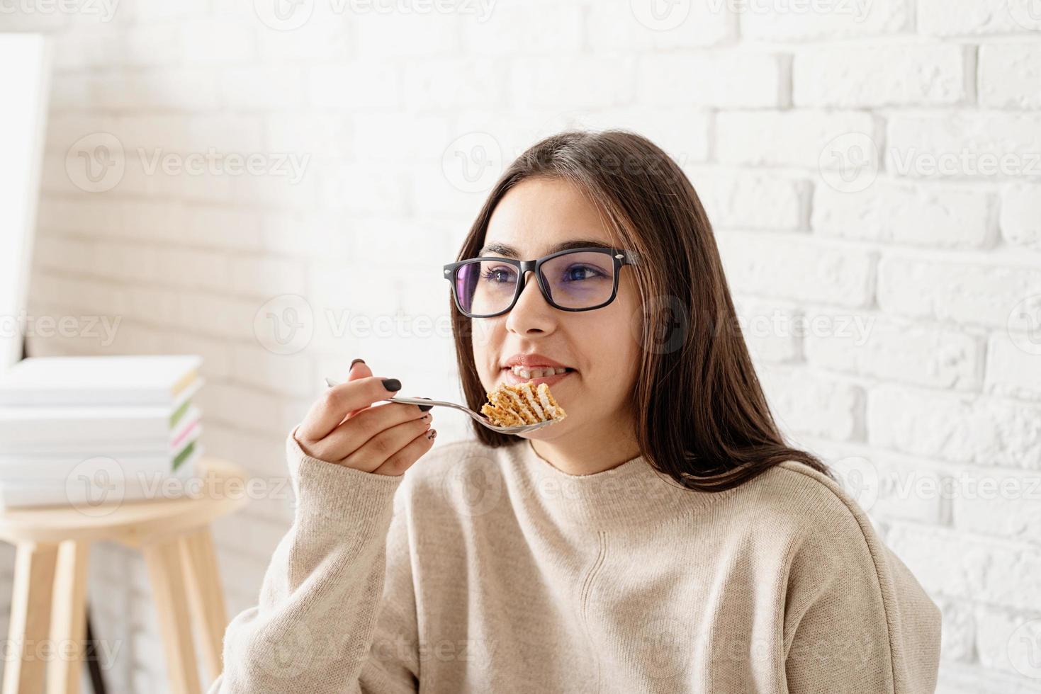 mulher sentada à mesa branca, comendo bolo e tomando café foto