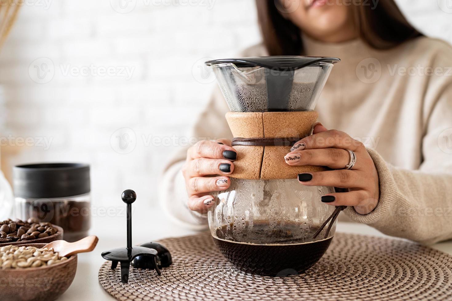 mulher fazendo café na cafeteira, despejando água quente no filtro foto