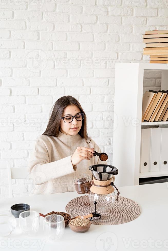 mulher despejando grãos de café moídos no filtro foto