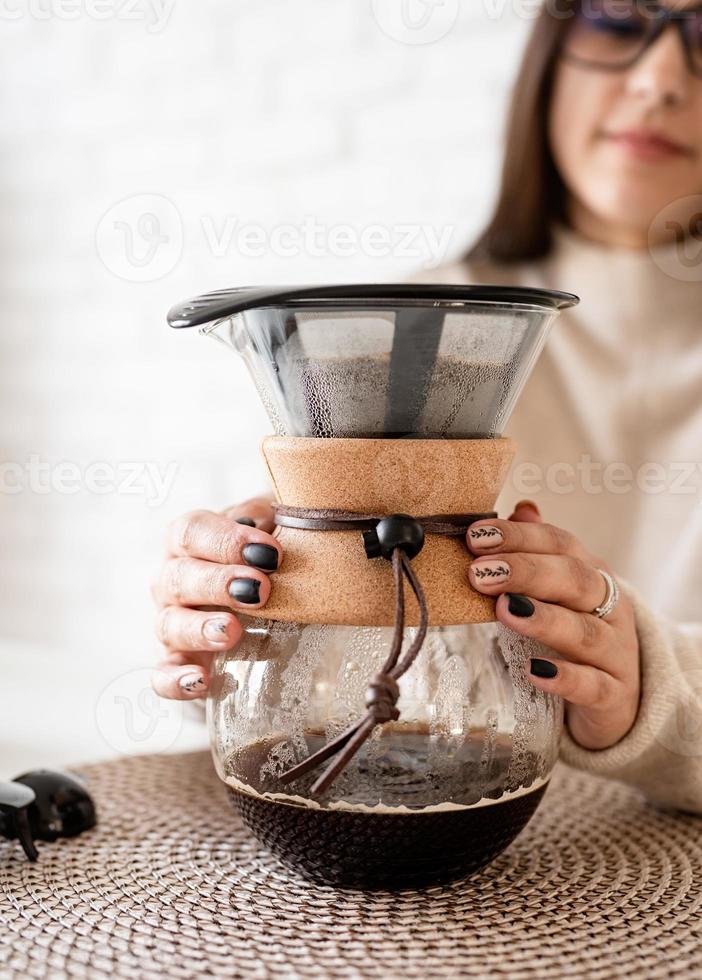 mulher fazendo café na cafeteira, despejando água quente no filtro foto