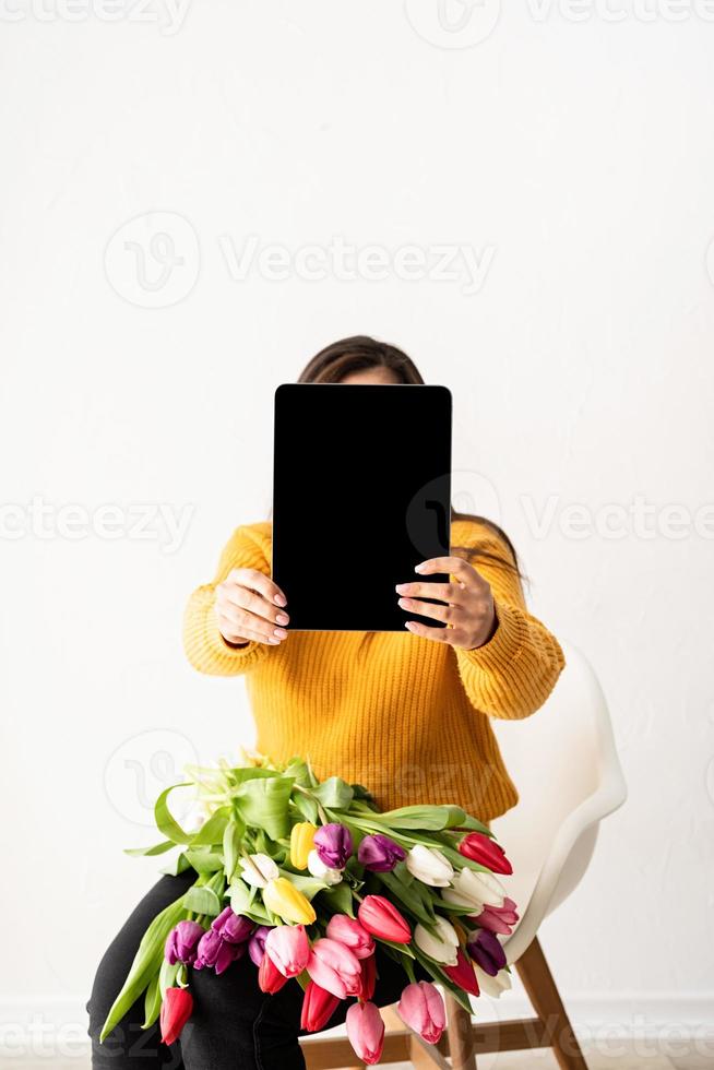 mulher com buquê de tulipas frescas e tablet digital em branco foto