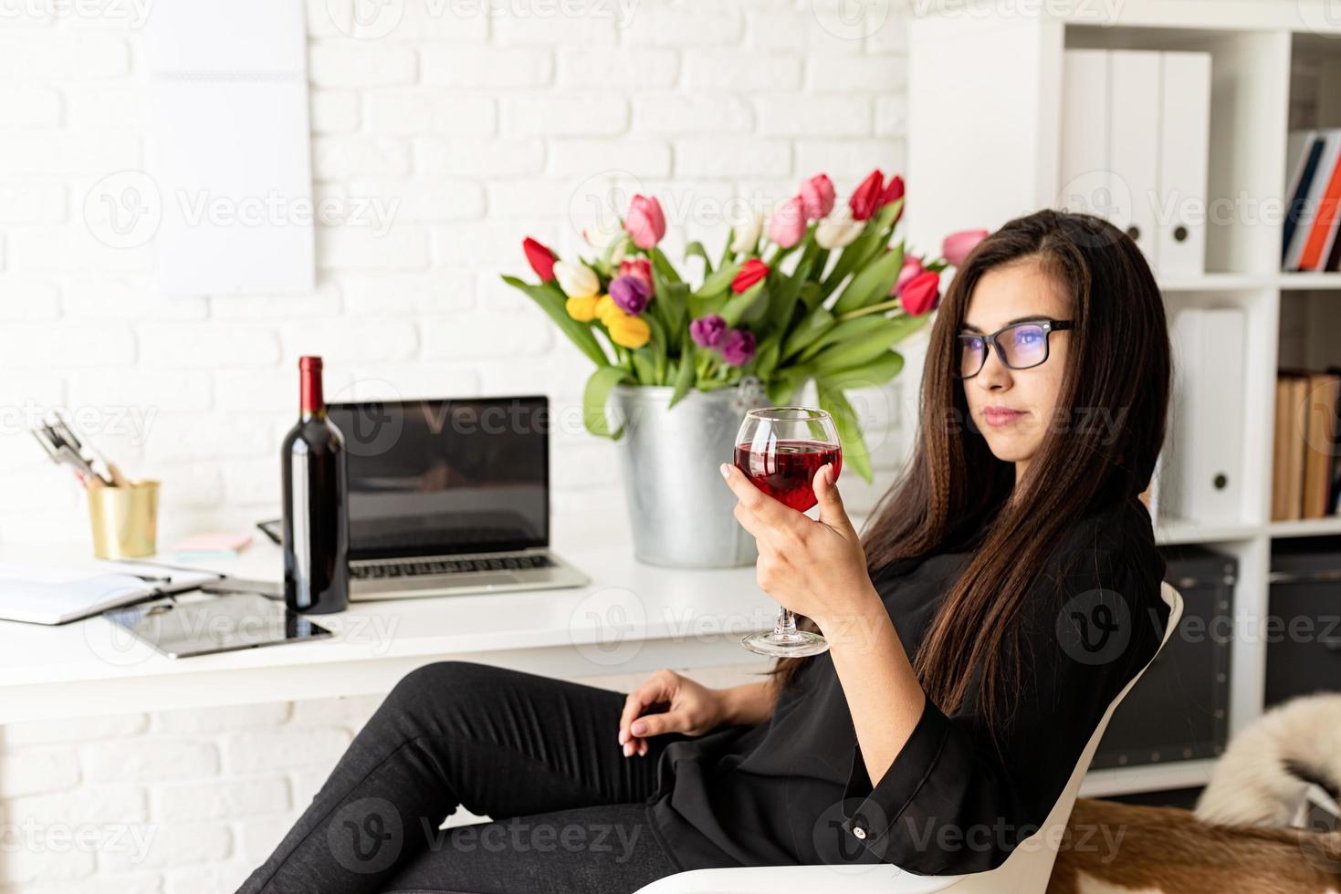 mulher de negócios bebendo vinho, comemorando no escritório em casa foto