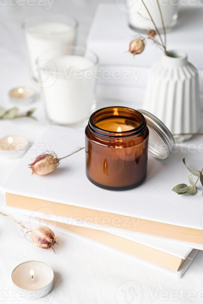 velas com folhas de eucalipto e flores secas na pilha de livros brancos foto