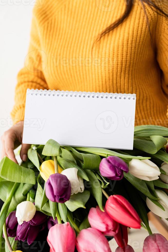 mulher com buquê de tulipas cor de rosa frescas e calendário em branco para simulação de foto