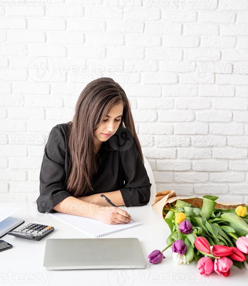 florista escrevendo em caderno ou calendário no escritório foto