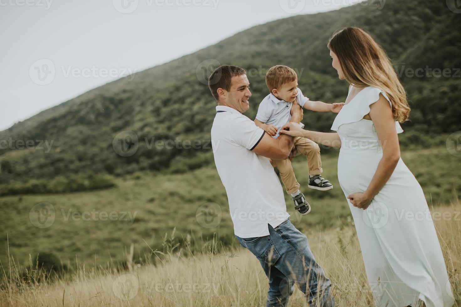 família jovem com garotinho fofo se divertindo ao ar livre no campo foto