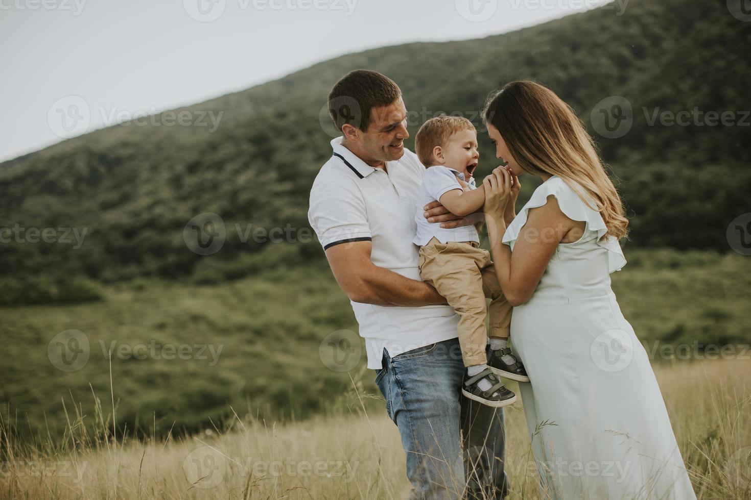 família jovem com garotinho fofo se divertindo ao ar livre no campo foto