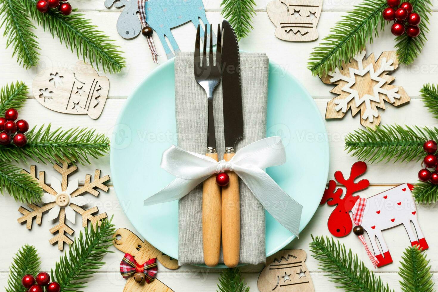 vista superior do jantar de ano novo em fundo de madeira festivo. composição de prato, garfo, faca, abeto e decorações. feliz natal conceito foto