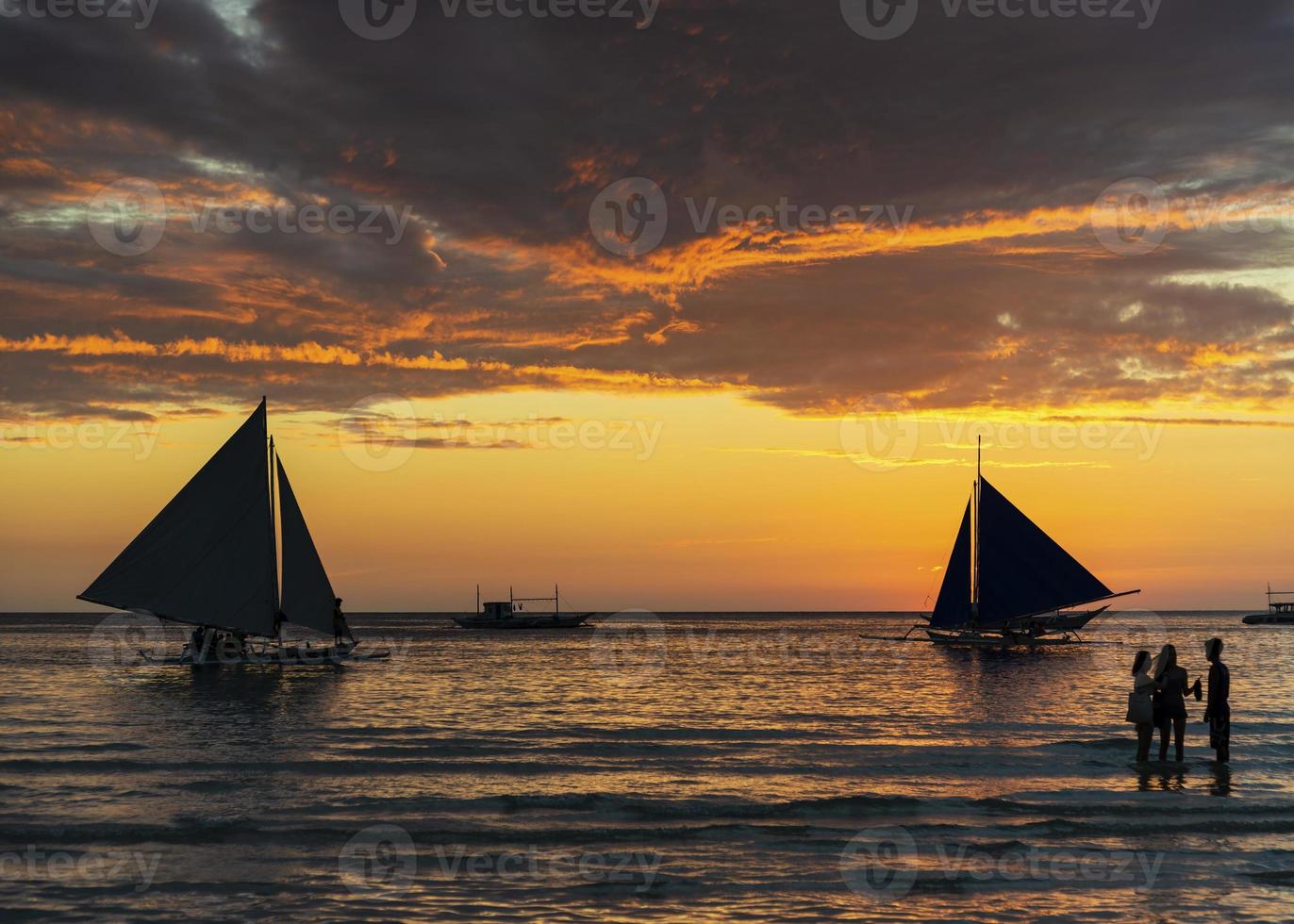 lindo pôr do sol tropical com barcos à vela e turistas na ilha de Boracay, nas Filipinas foto