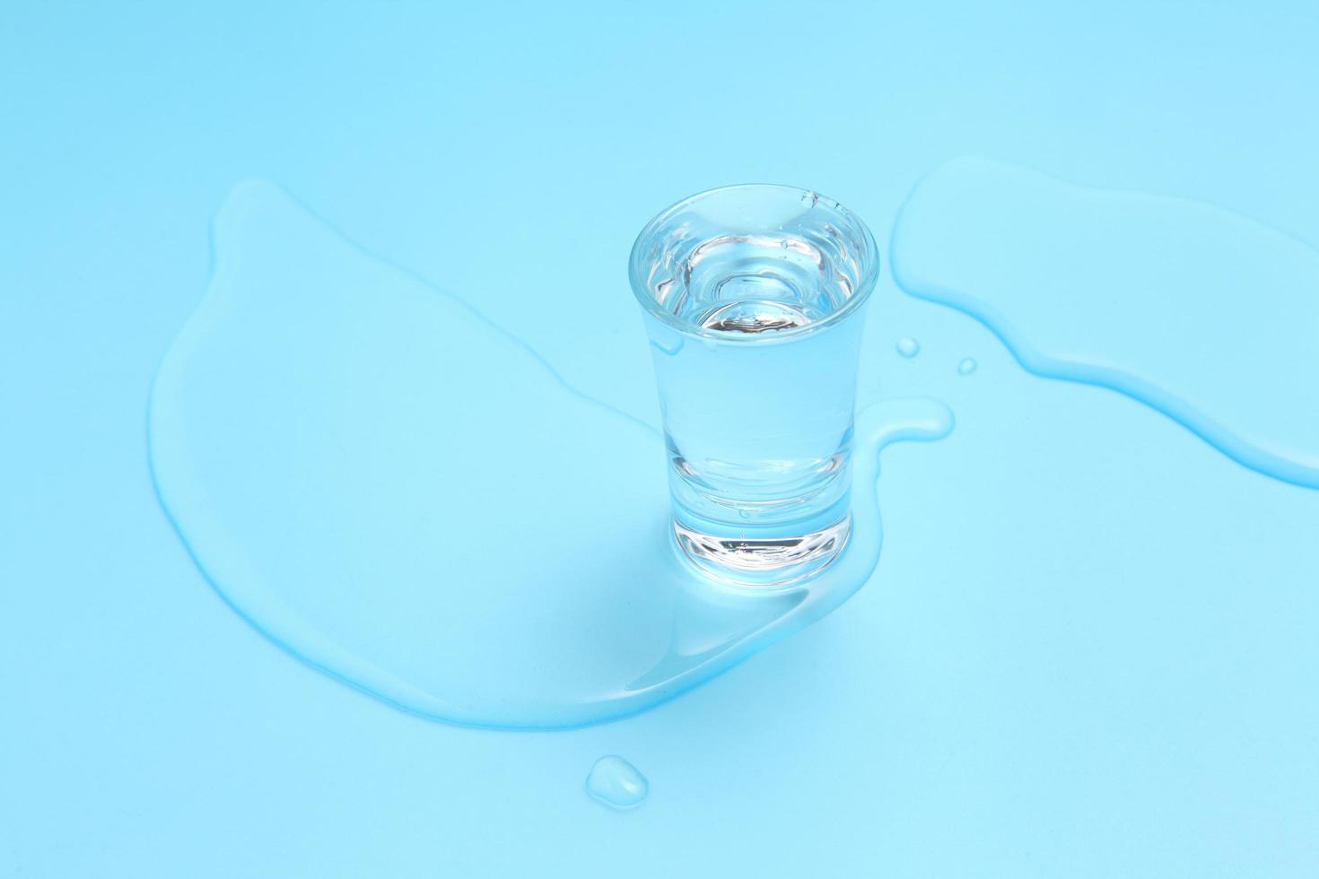 vodka em copo de shot no fundo azul foto