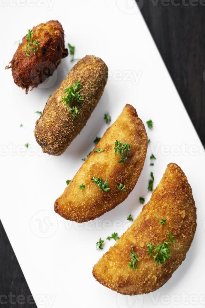 petiscos tradicionais portugueses mistas de tapas fritas no prato com rissole de camarão, croquete de bife e pepita de bacalhau foto
