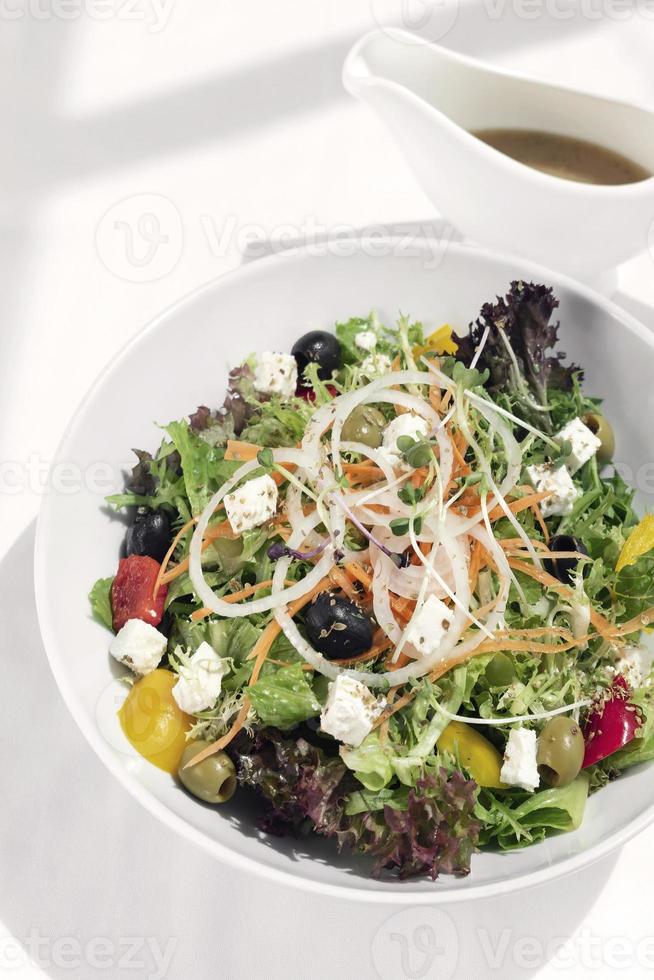 Salada grega com queijo feta e azeitonas com vinagrete cítrico na mesa de madeira foto