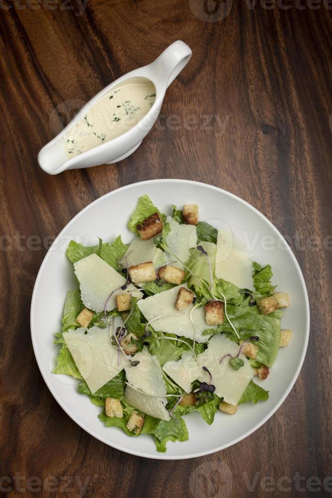 salada césar com queijo parmesão e croutons na mesa de madeira foto