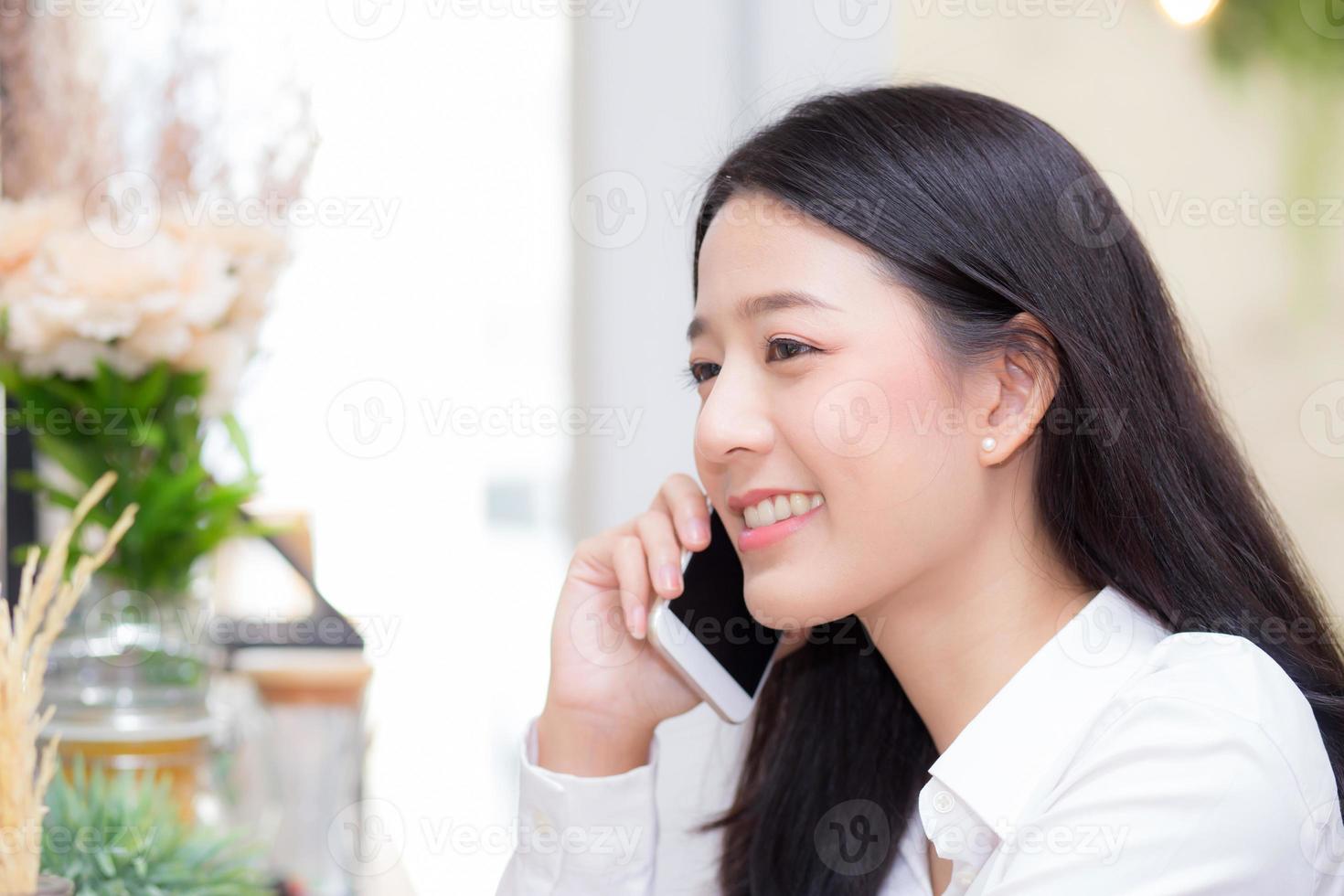 jovem mulher asiática falando de telefone e sorriso no café. foto