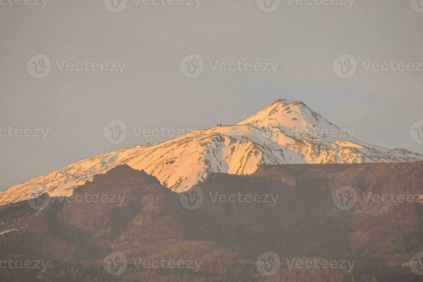 uma montanha com neve em topo às pôr do sol foto