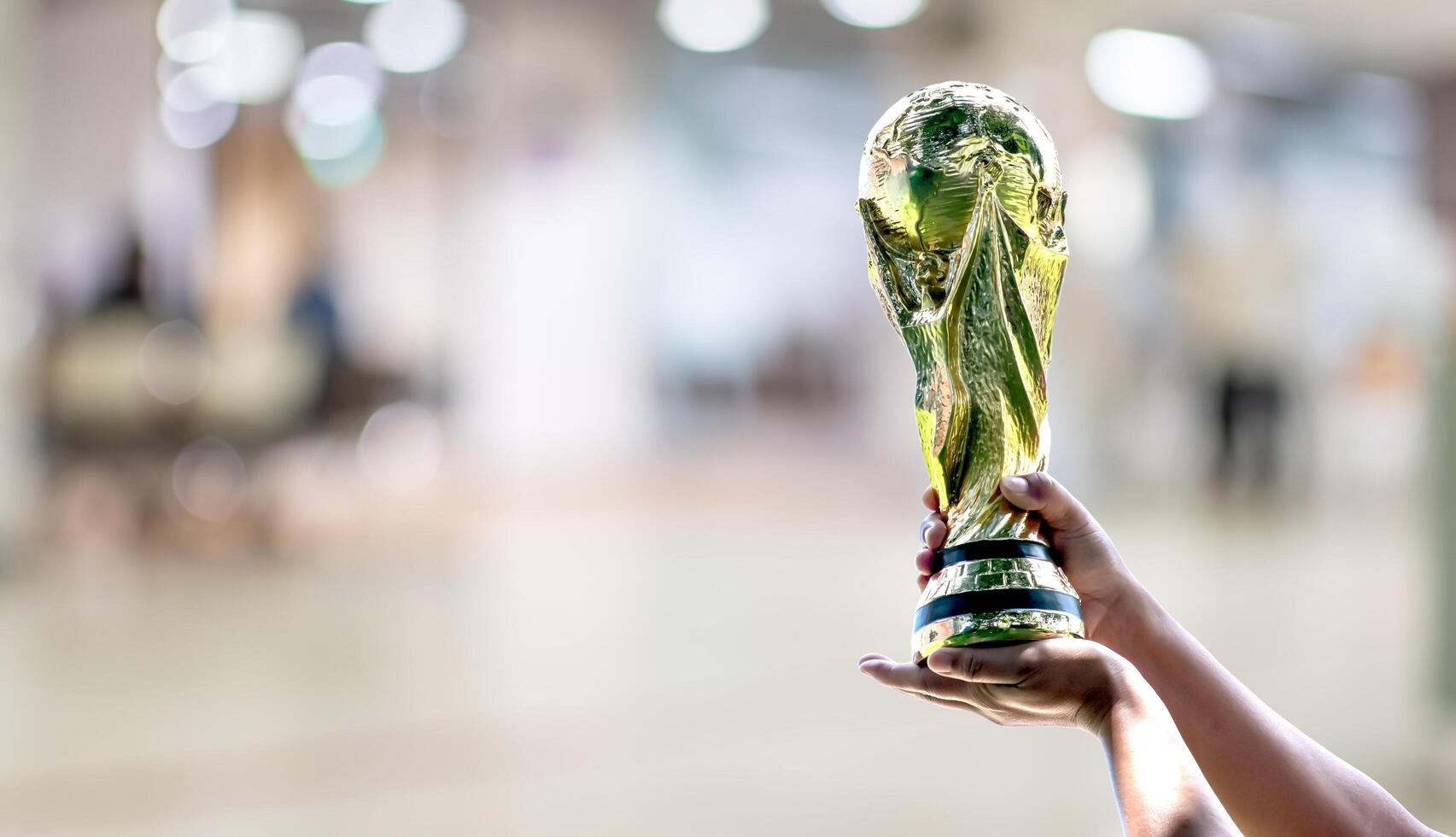 mundo copo com borrado fundo. mão segurando uma mundo copo vencedora troféu. a conceito para mundo copo dentro Catar. cópia de espaço em esquerda para Projeto ou texto foto