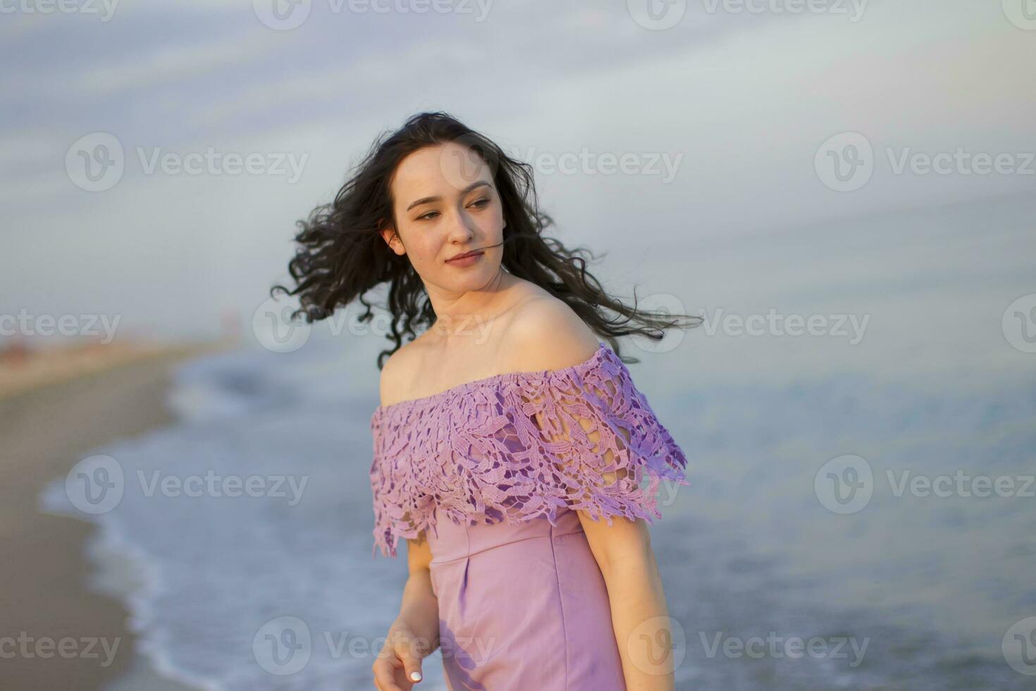 jovem comum menina dentro roupas com aberto ombros fluindo cabelo vai ao longo a mar foto