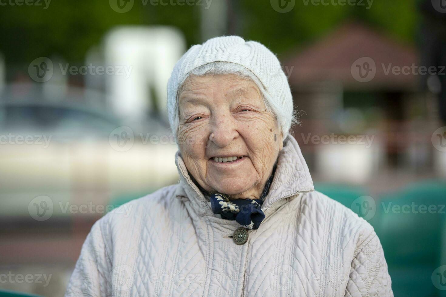 idosos mulher com rugas dentro uma tricotado chapéu, sorridente, olhando às a Câmera. a oitenta e cinco ano velho mulher. foto