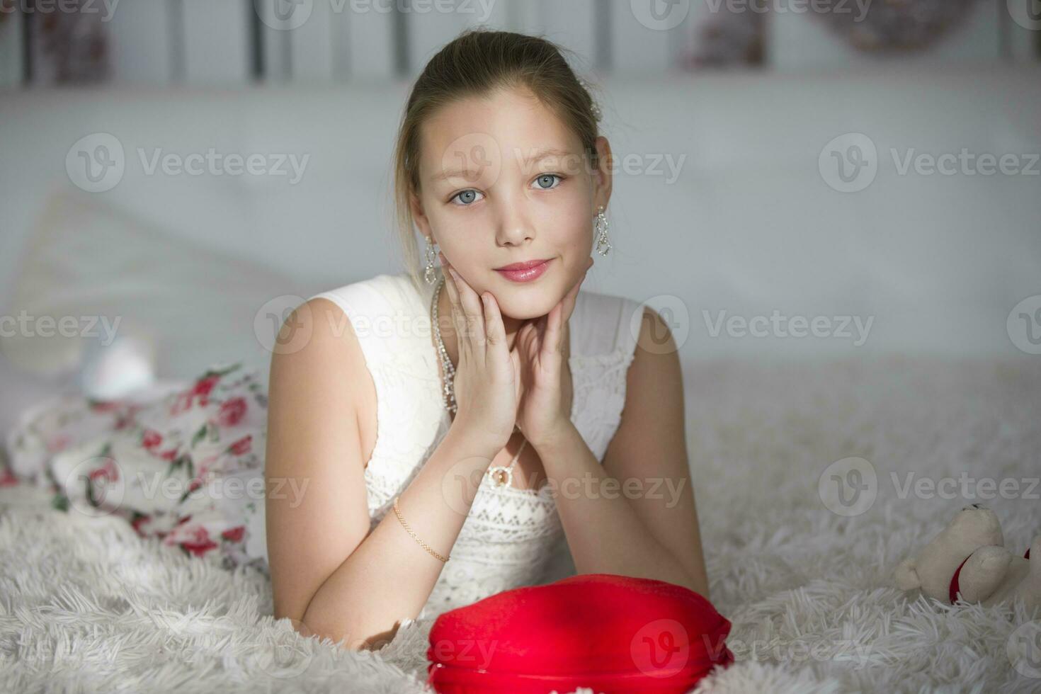 muito lindo adolescente menina deitado em uma cama com uma vermelho coração travesseiro.jovem senhora foto