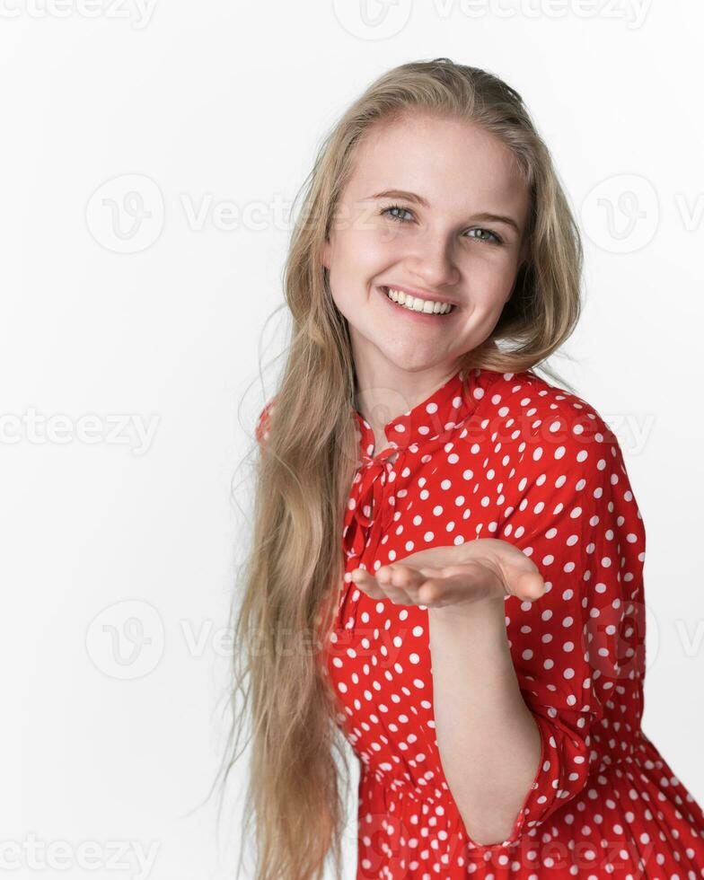 sorridente loiro mulher alongar dela 1 Palma para Câmera. retrato do modelo dentro vermelho polca ponto vestir foto