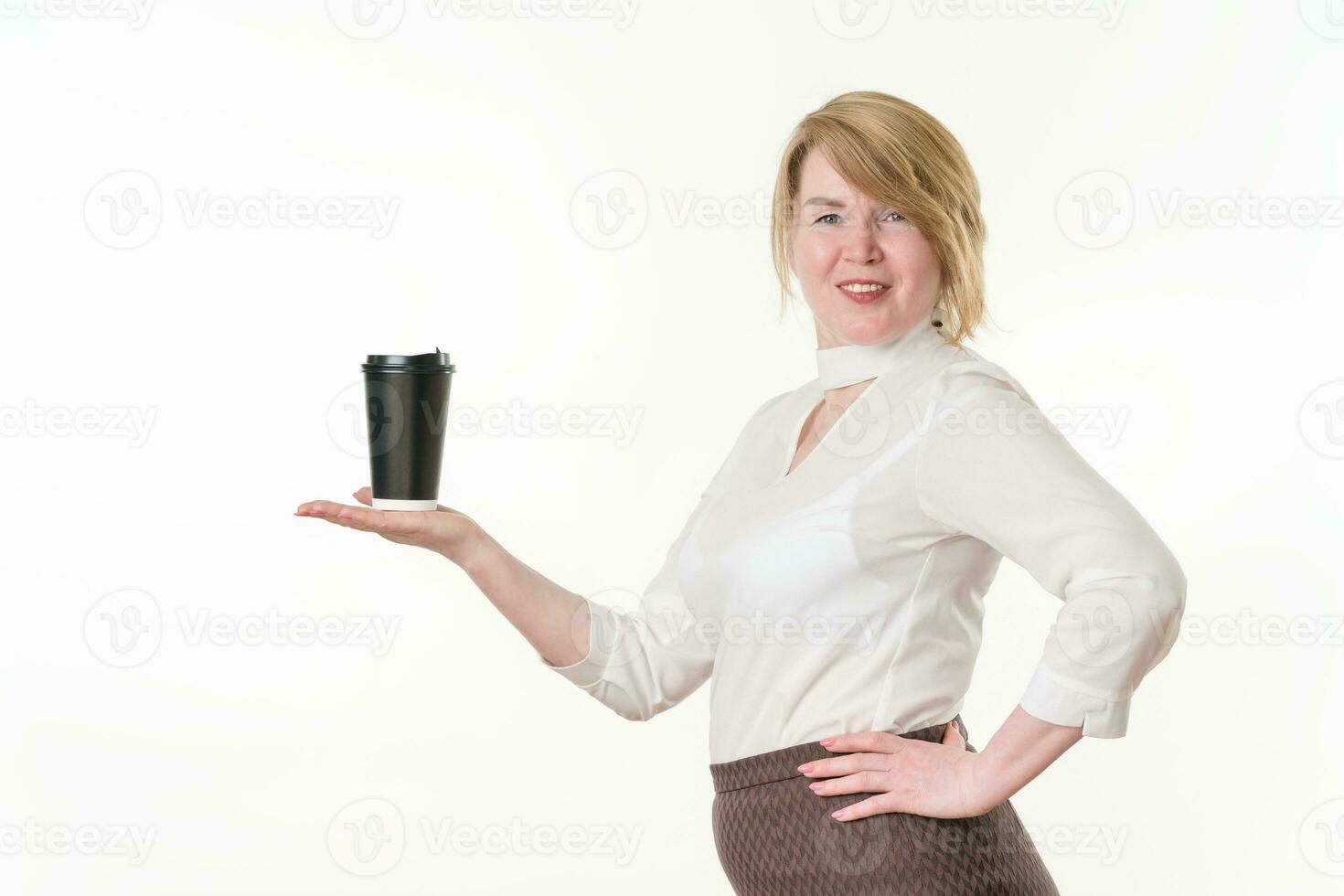 sorridente mulher detém Preto papel descartável copo para café dentro estendido mão e olhando às Câmera foto